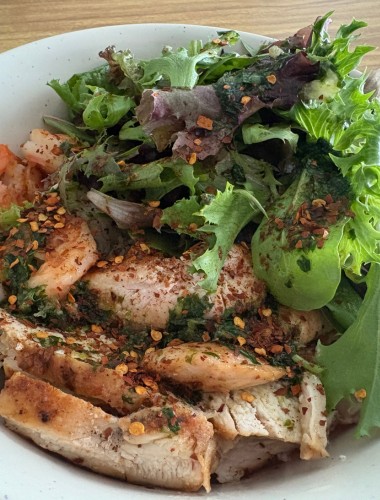 Sliced fried pork with mixed greens and sprinkled Thai dried chili peppers served over rice noodles