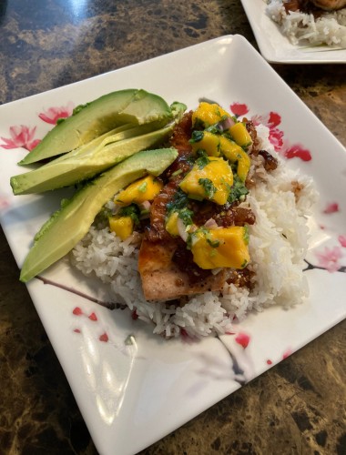 Grilled salmon over jasmine rice topped with fresh mango salsa and sliced avocado