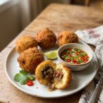 Golden Cuban papas rellenas stuffed with picadillo, served with chile dipping sauce.